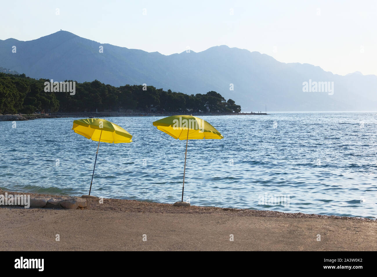 Zwei gelben Sonnenschirme am Strand. Perfekte Ferien Konzept. Küstenlandschaft. Entspannend. Helle Meer Wasser Hintergrund. Stockfoto