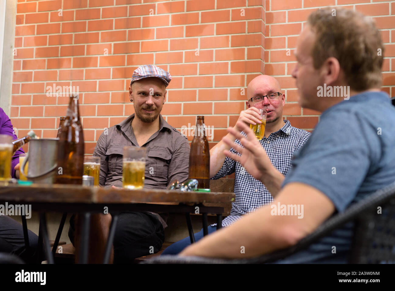Gruppe von Männern im Freien sitzt und spricht beim Bier trinken. Stockfoto
