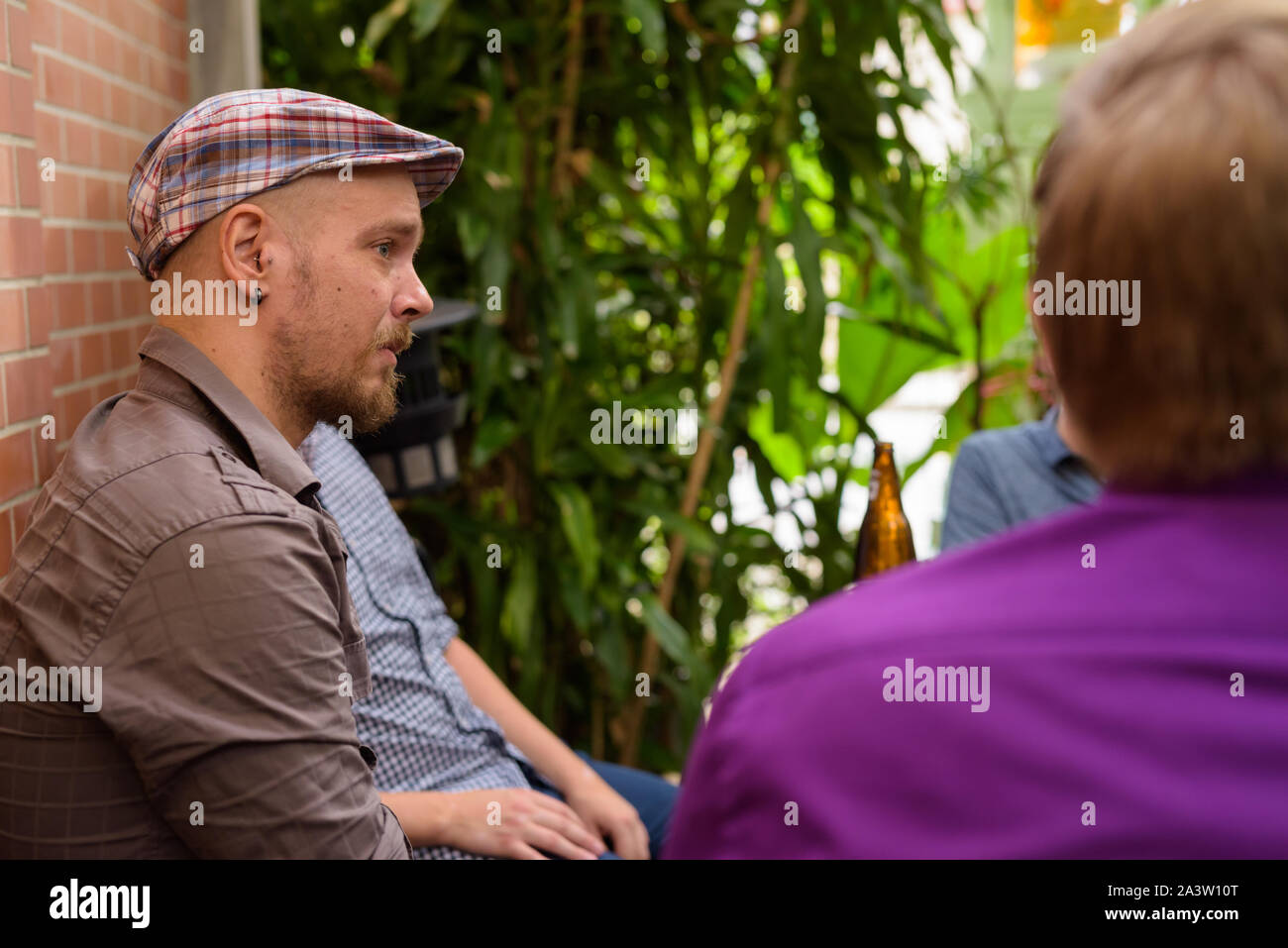 Hipster Mann sitzt draußen und mit Freunden zu reden Stockfoto