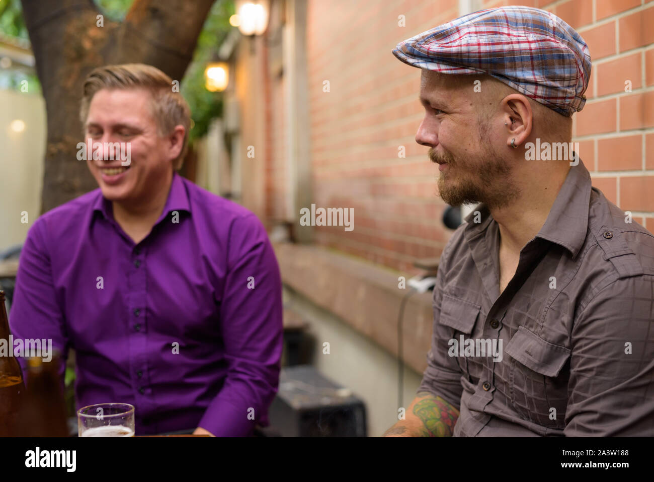 Zwei Mann Lachen beim Trinken von Bier mit Freunden Stockfoto