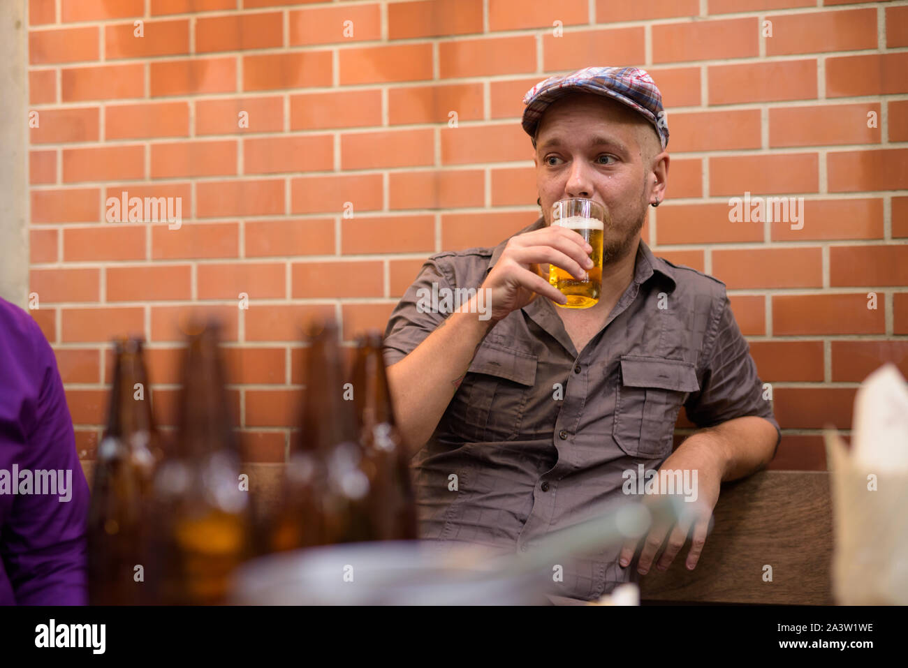 Happy hippie Mann draußen sitzen und Bier trinken. Stockfoto