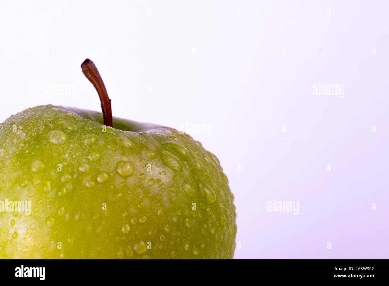Grüner Apfel mit Wassertropfen auf Weiß Stockfoto