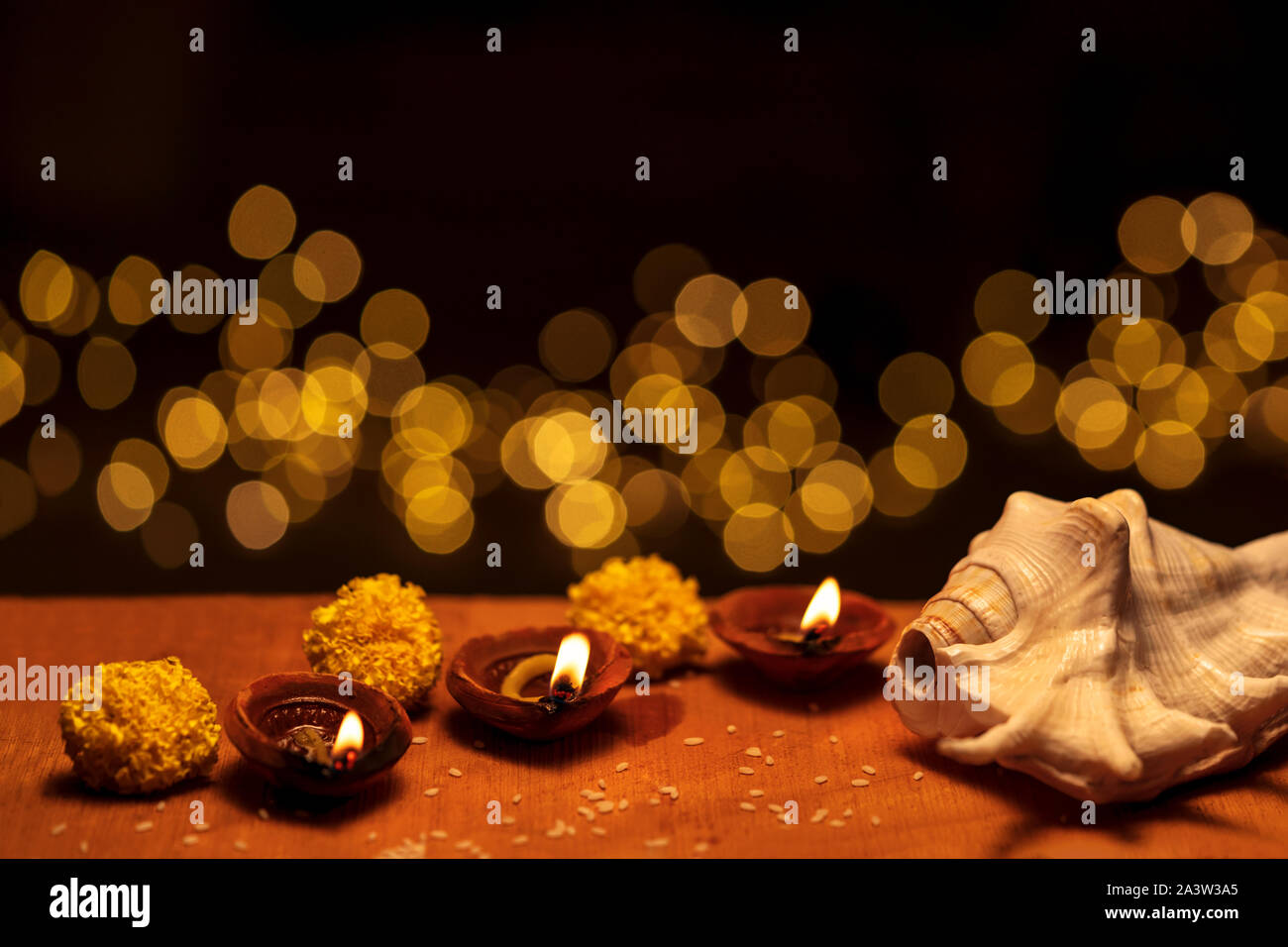 Diwali diya Tonlampen mit Blumen und shankha brennende oder glühende auf einer hölzernen Hintergrund in Schwarz mit bokeh Lichter und kopieren Raum isoliert eingerichtet Stockfoto