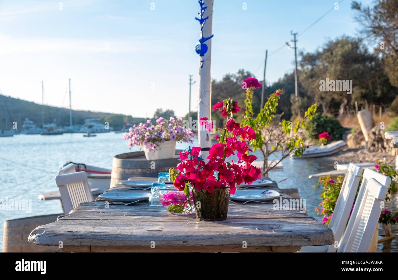 Seaside Holztisch und Stühlen öffnen Cafe Restaurant im Freien in Gumusluk, Bodrum - Türkei am Meer. Sommer Urlaub im Resort. Stockfoto