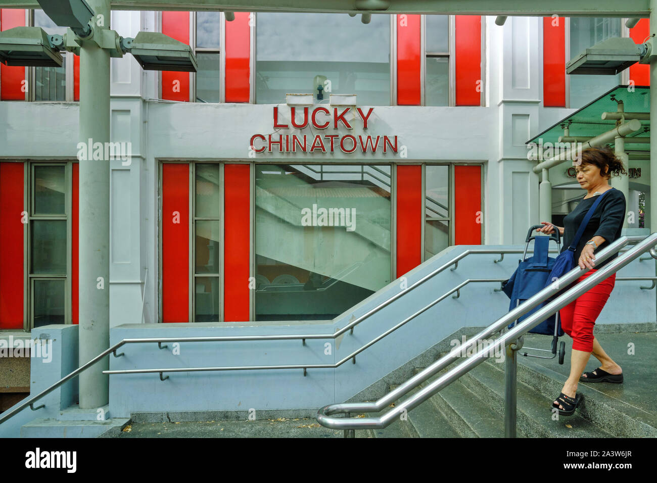 Eine Frau geht eine Fußgängerbrücke am glücklichen Chinatown Mall in Chinatown, Singapur, das rote Ihrer Hose passend zu den Mall's 'Lucky' rote Streifen Stockfoto