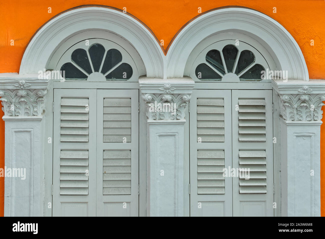 Gewölbt, weiß, Doppel-, oder fast "twin" Art von Windows in einem orangefarbenen Gebäude, an der Ecke Neue Brücke Rd./Pagode St, in Chinatown, Singapur Stockfoto