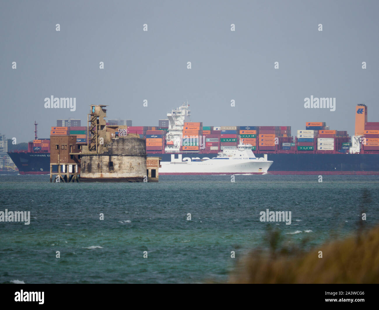 Queenborough, Kent, UK. 10. Oktober, 2019. Die markante Korn Turm, die oft als "Nr. 1 der Themse' gerade bis zum Verkauf zu einem Orientierungspreis von £ 2 Millionen, die vor kurzem auf der Internetseite Zoopla aufgeführt wurde von Agenten Sparemove. Um 1855 erbaut, kann es nur bei Ebbe von einem kleinen Damm zugegriffen werden. Es liegt an der Mündung der Themse und Medway zwischen der Insel von Korn und Sheerness. Containerschiff Valparaiso Express übergibt die kleineren Caroline Russ. Credit: James Bell/Alamy leben Nachrichten Stockfoto