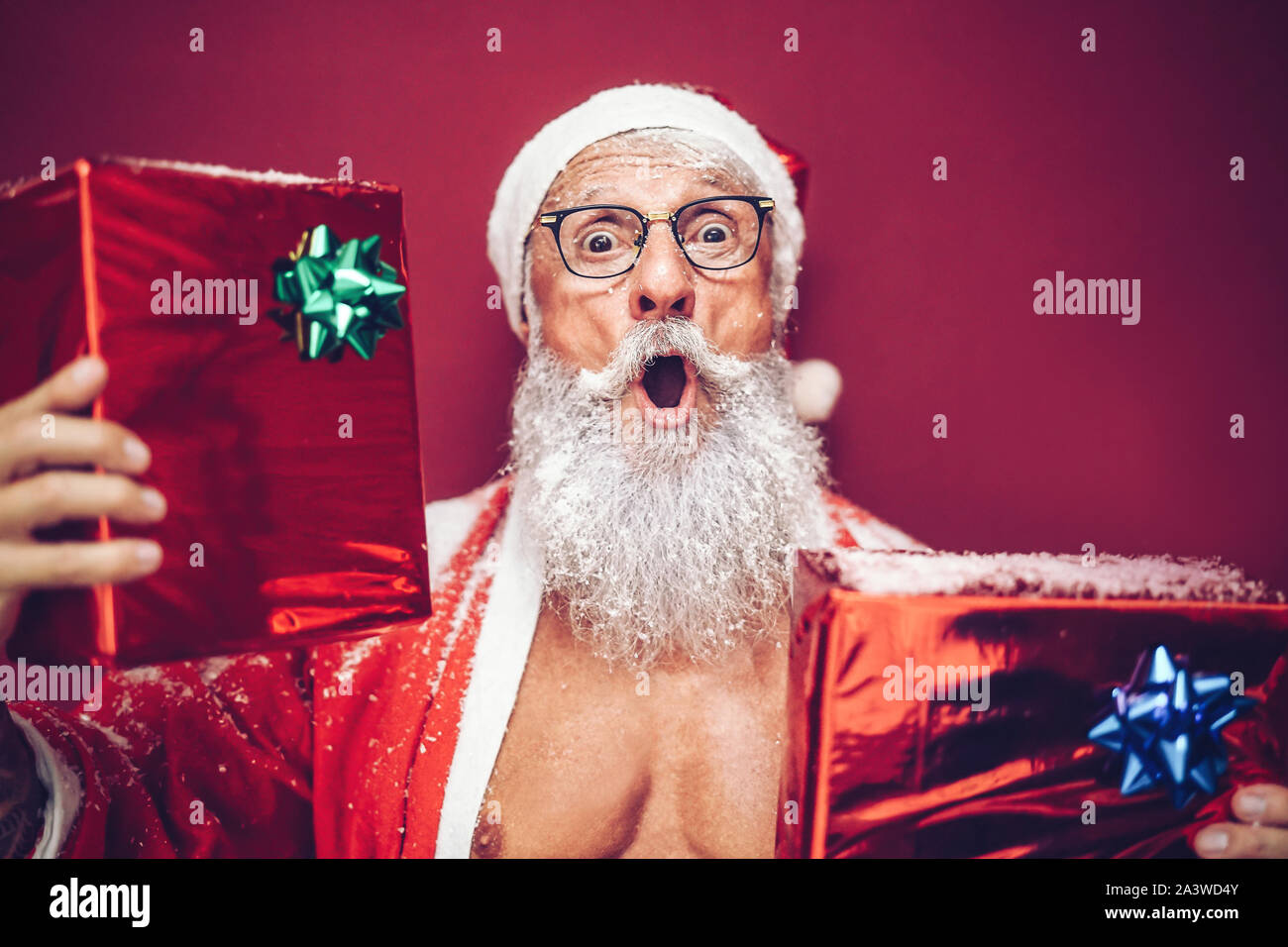 Happy fit Weihnachtsmann lachend und Weihnachten Geschenke - trendige Bart tattoo hipster Senior tragen xmas Kleidung und Holding präsentiert Stockfoto