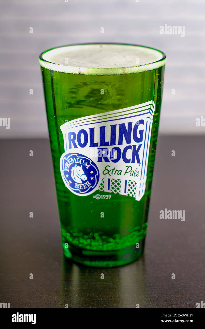Rolling Rock Extra Pale Pint Bier auf einem Schwarzen Tisch mit einer Ziegelmauer vertikale Ansicht. Stockfoto