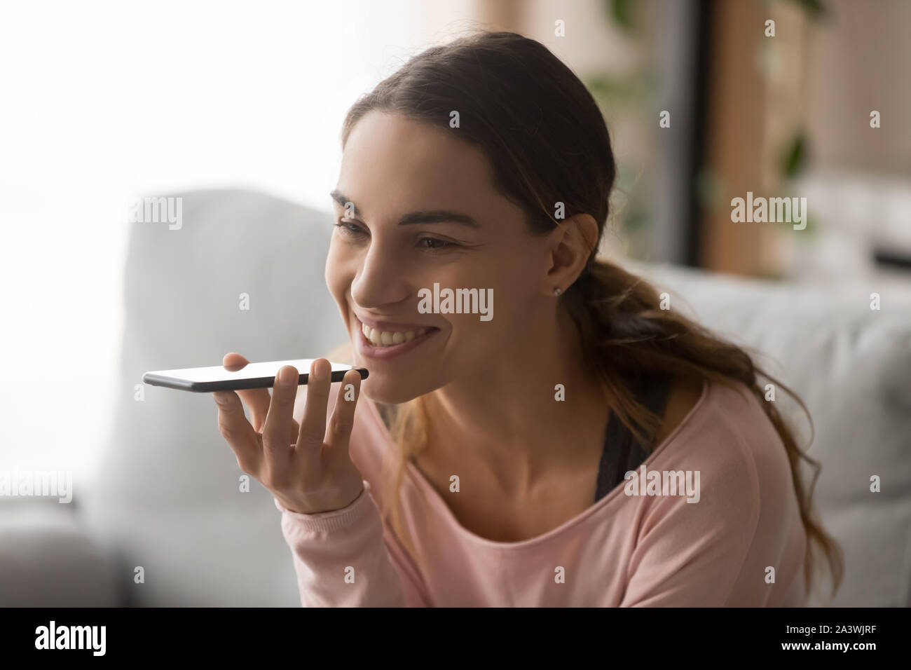 Lächelnde Frau aktivieren Sie virtuellen Digital Voice Assistant auf Handy Stockfoto