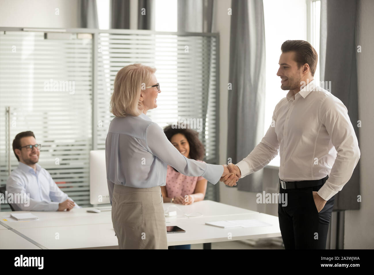 In coworking im mittleren Alter Chef Begrüßung neuer Mitarbeiter mit Handshake Stockfoto