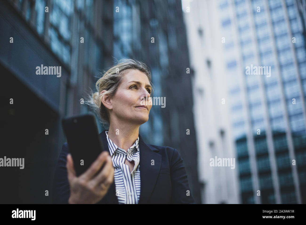Geschäftsfrau zu Fuß in der Stadt mit Smartphone Stockfoto