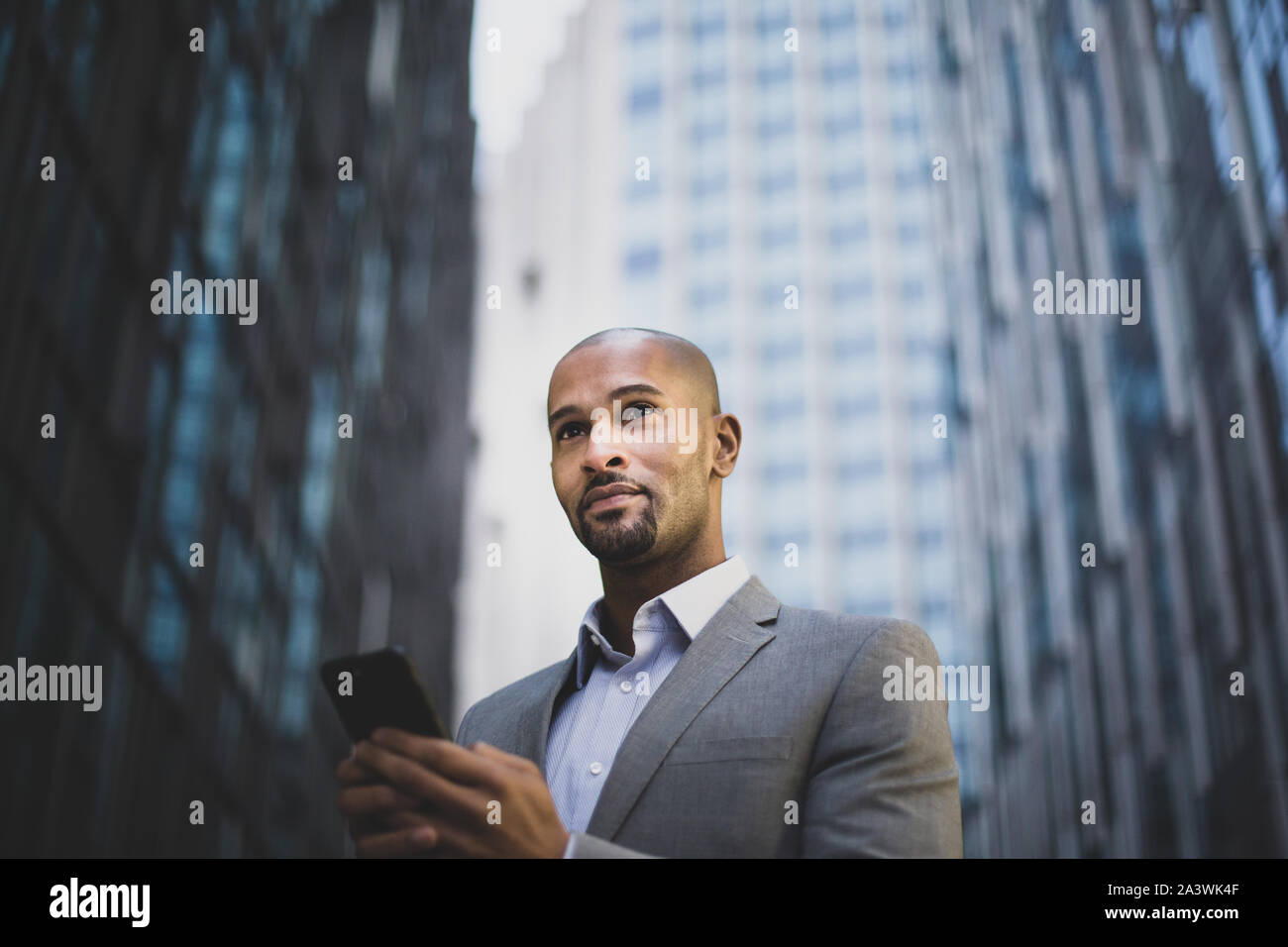 Unternehmer gehen in der Stadt mit Smartphone Stockfoto