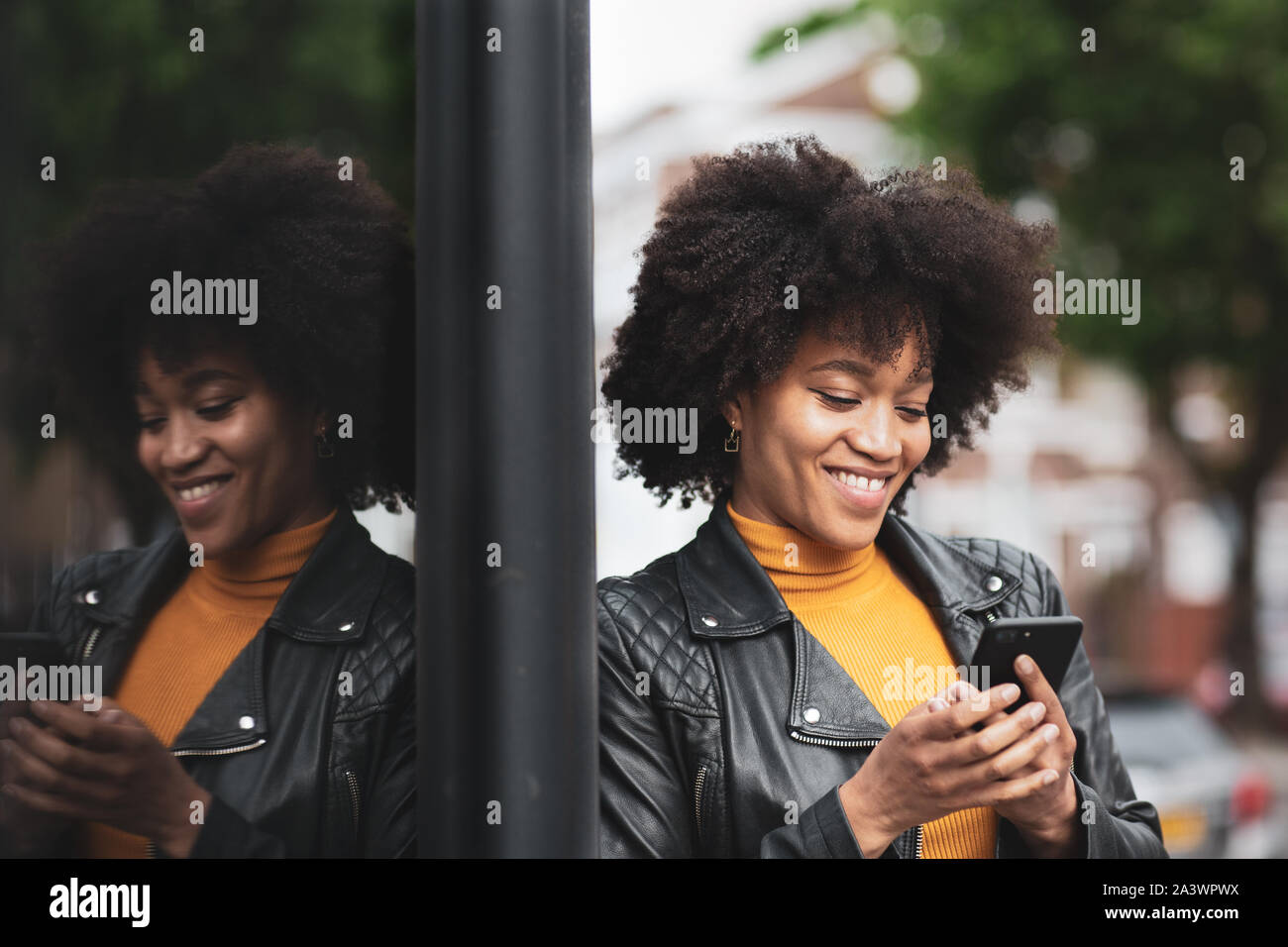 Afrikanische amerikanische junge erwachsene Frau mit Smartphone in der Stadt Stockfoto
