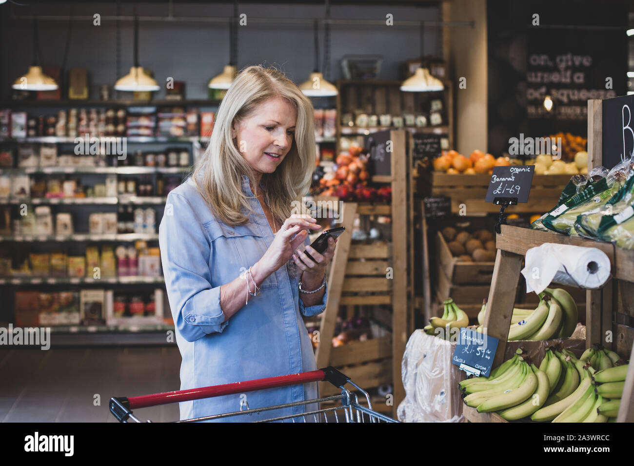 Ältere Frauen tun, wöchentliche Lebensmittelgeschäft mit Smartphone Stockfoto