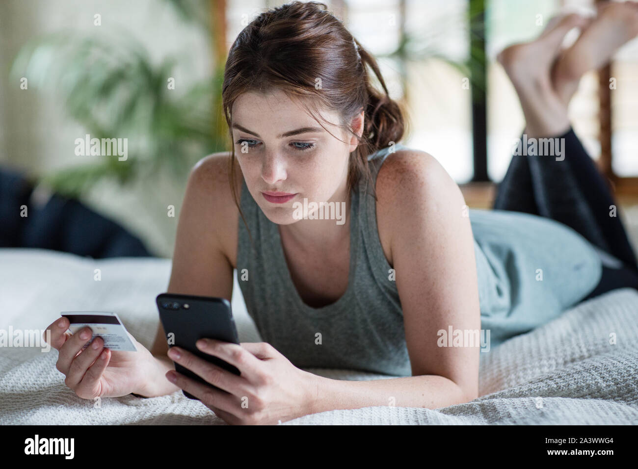 Junge erwachsene Frau Shopping auf dem Smartphone Stockfoto