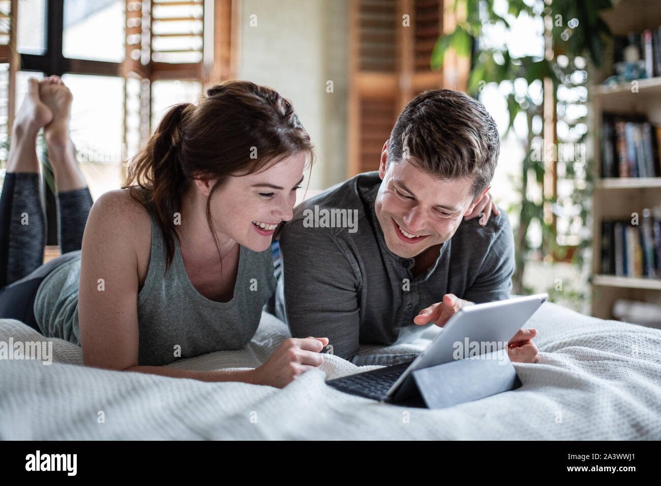 Junge erwachsene Paare an einem digitalen Tablet zusammen im Bett suchen Stockfoto