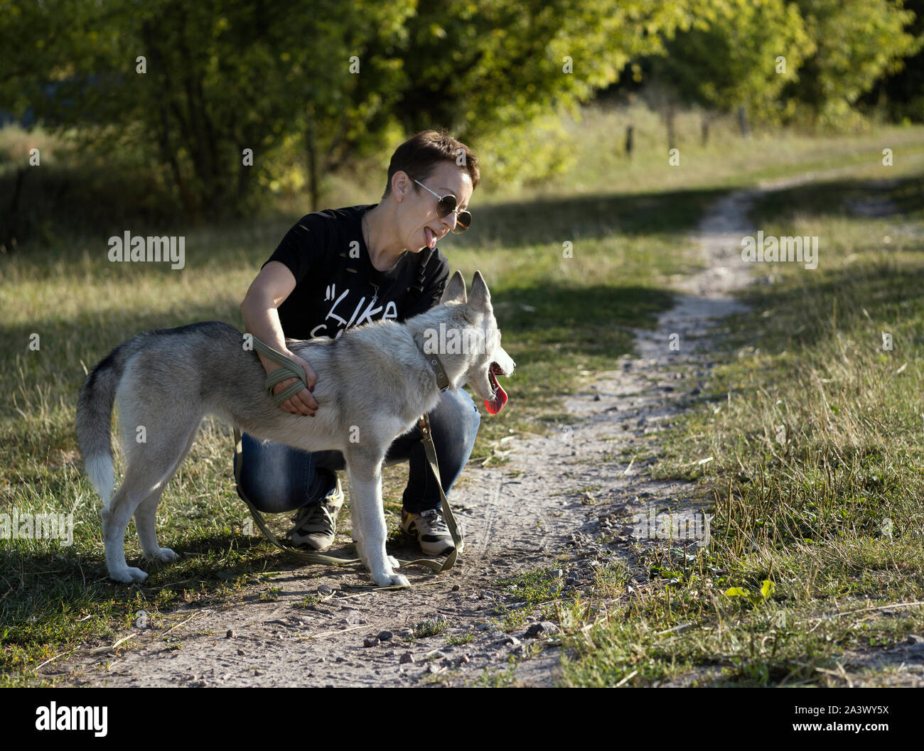 Kurze behaarte Frau necken verspielten Husky Hund, zeigen Sie ihm Ihre Zunge, spielen mit ihm. Pet Care Concept Stockfoto