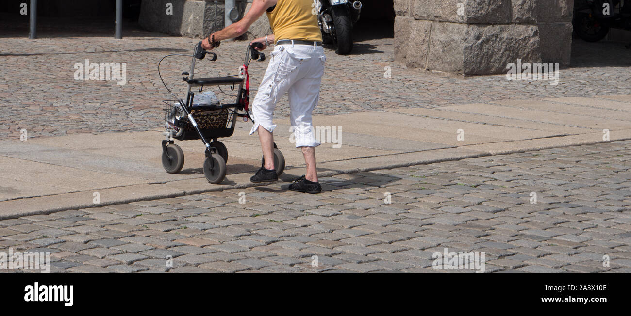 Alte Frau kreuzt eine Straße mit dem rollator Stockfoto