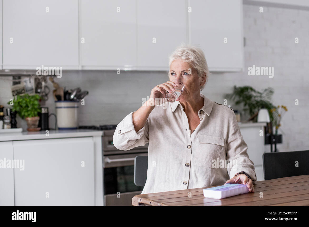 Reifen erwachsenen Frau, die Einnahme von Medizin zu Hause in der Küche Stockfoto