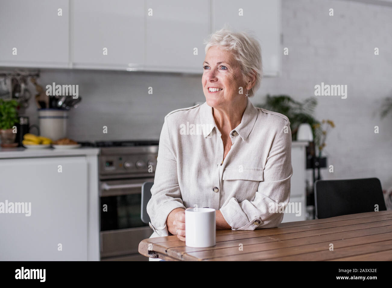 Reifen erwachsenen Frau Blick aus Fenster mit einer Tasse Kaffee Stockfoto