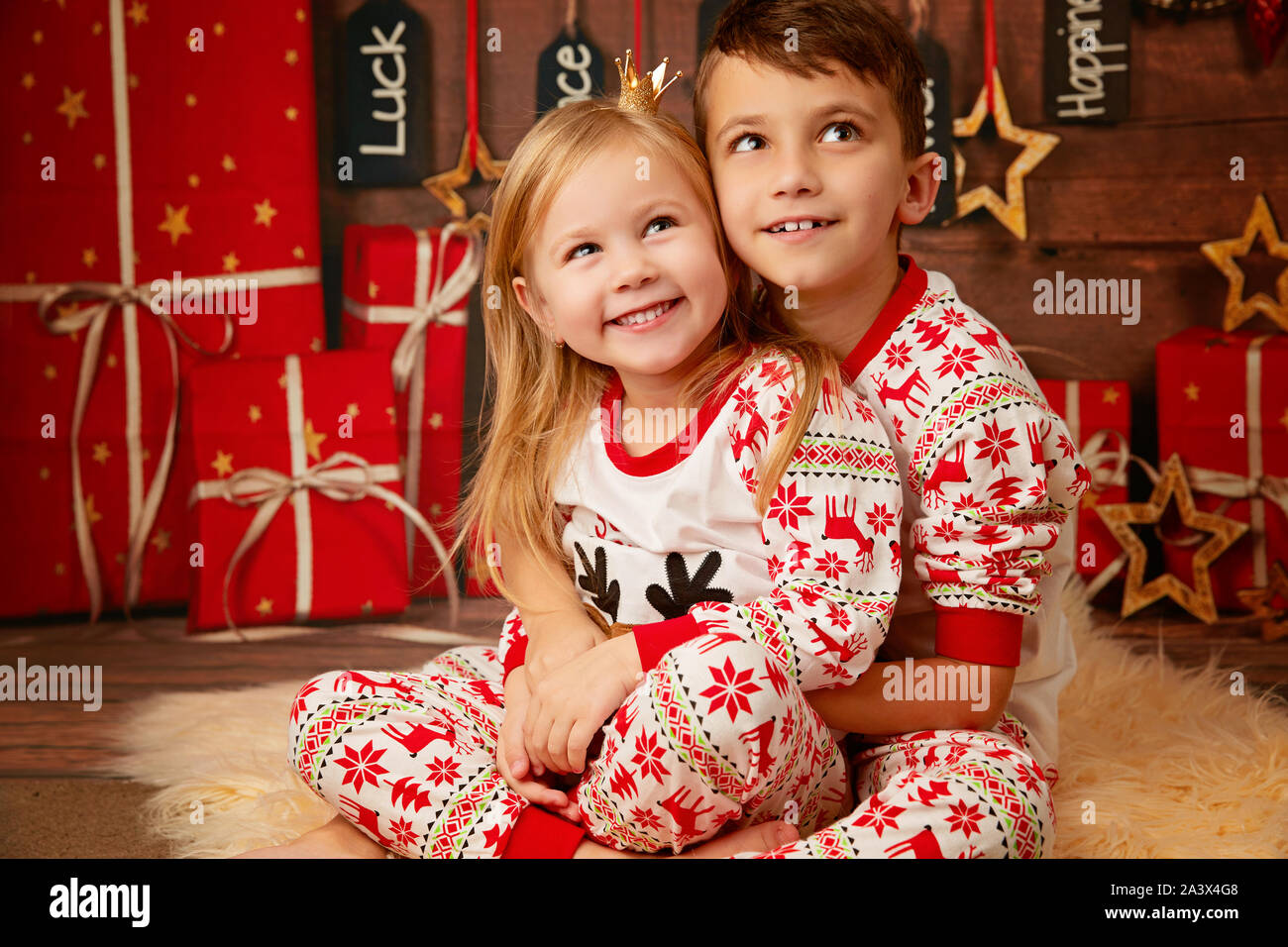 Glückliche kleine Bruder und Schwester in Weihnachten Schlafanzug warten auf Geschenke an Heiligabend Stockfoto