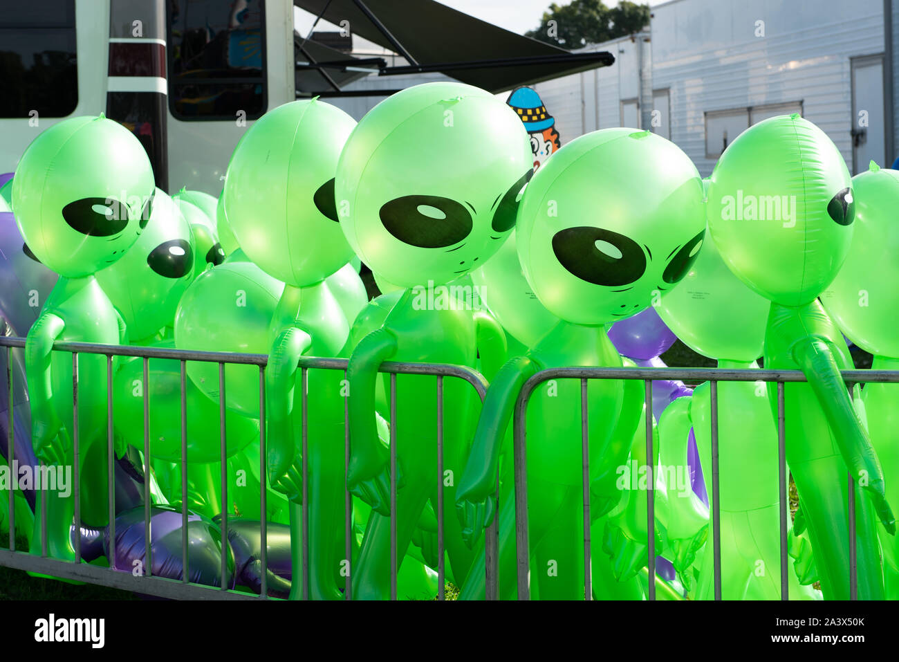 Aufblasbare grüne Martian Aliens stehen an einem sonnigen Sommertag in Reihe neben einem Anhänger auf der Goschen Bezirksmesse. Stockfoto