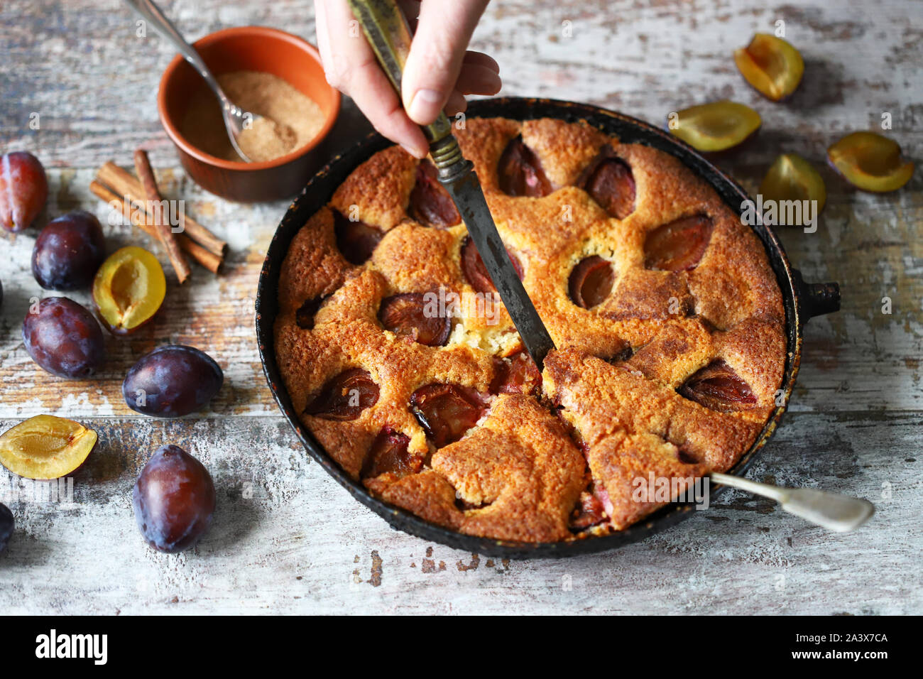 Männer Hände Pflaumenkuchen mit Messer und Gabel. Hausgemachte Pflaumenkuchen. Herbst kochen. Selektive konzentrieren. Makro. Stockfoto