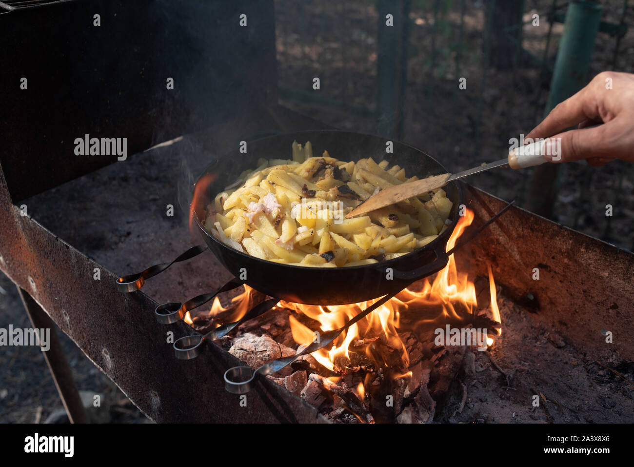 Hot big wok pfanne voller Fried leckere Kartoffel auf das Feuer im Wald.  Gebratene Kartoffeln auf einem Feuer in einem Wald in der Pfanne.  Köstliches Essen im Freien für Stockfotografie - Alamy