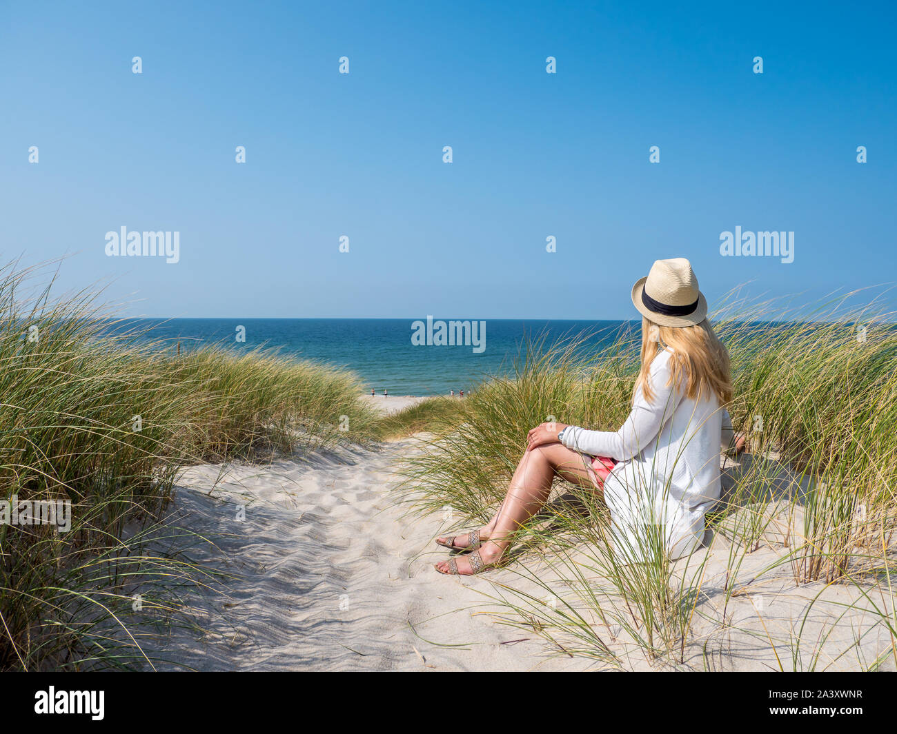 Frau sitzt im Sand auf das Meer Stockfoto