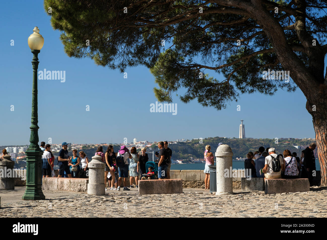Viele Touristen an einem Aussichtspunkt auf dem Gelände von Sao Jorge (Castelo de Sao Jorge) in Lissabon, Portugal. Cristo Rei Monument ist im Hintergrund. Stockfoto
