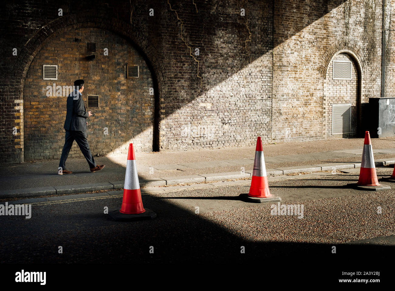 Mann im Anzug gehen unter einer Brücke, London, UK Stockfoto