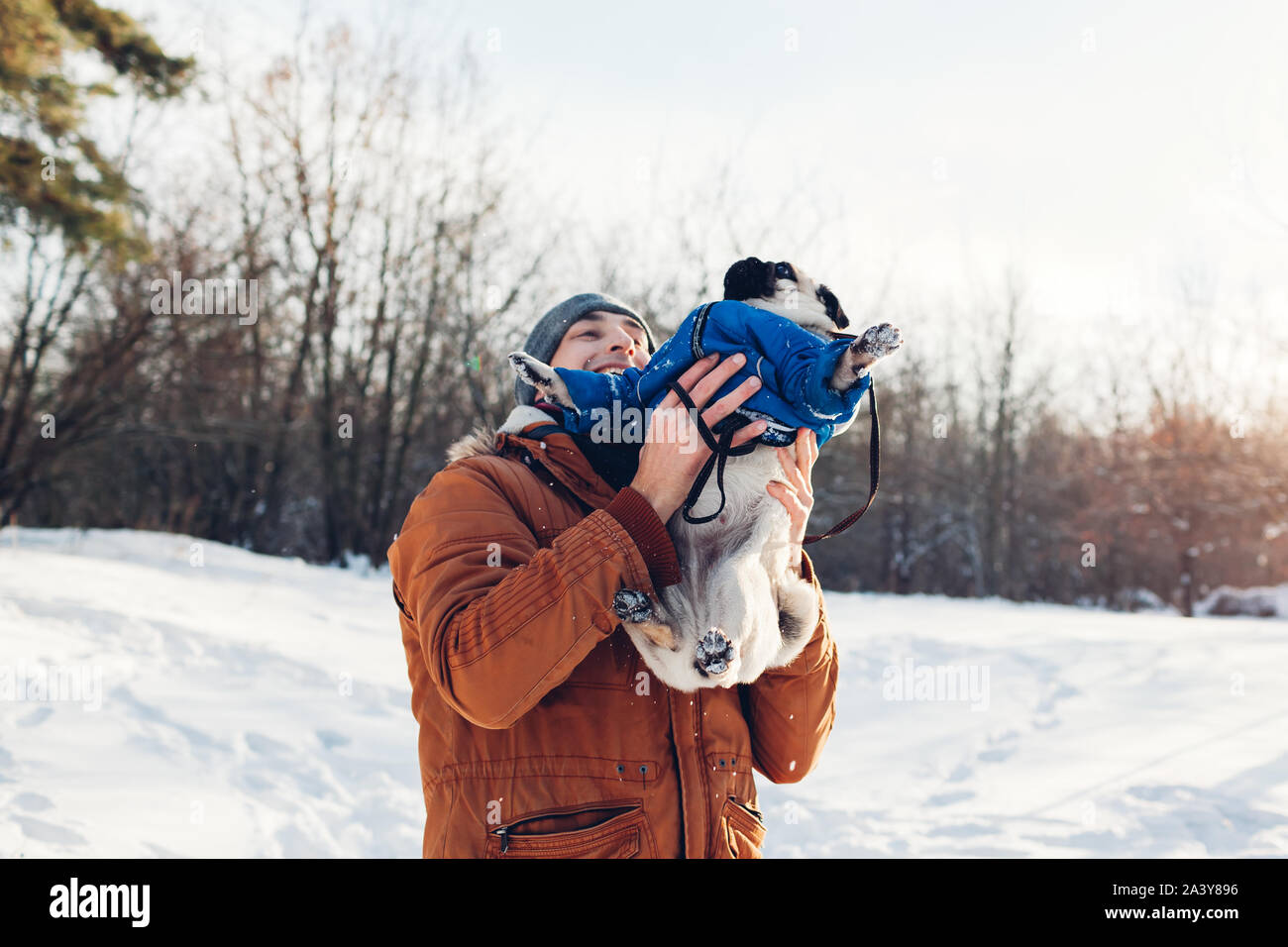 Mops Hund wandern mit seinem Meister. Mann spielt mit seinem Haustier und Spaß haben. Welpen tragen Winter Mantel. Stockfoto