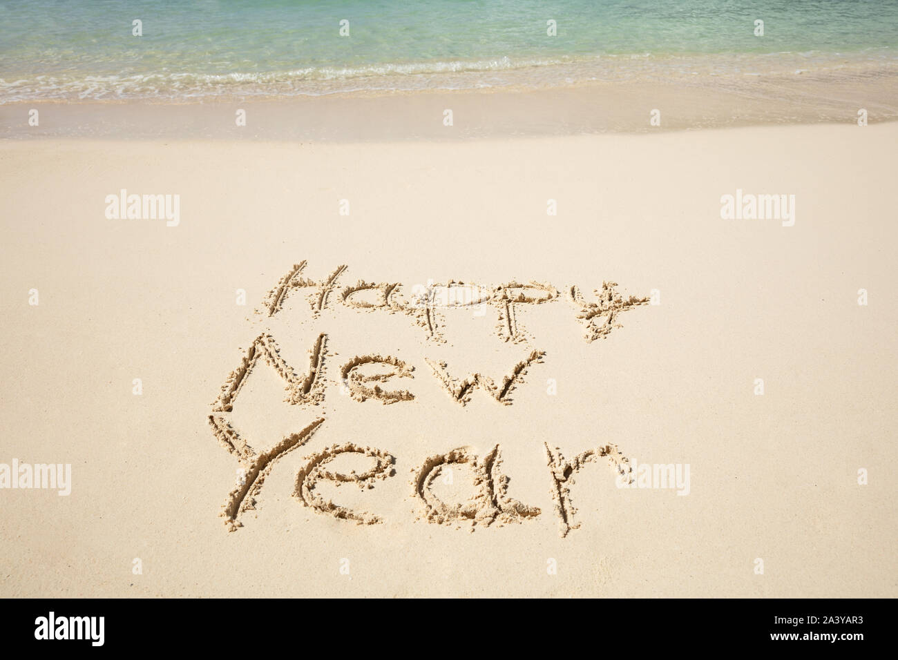 Frohes Neues Jahr Text auf Sand in der Nähe des Meer am Strand geschrieben Stockfoto