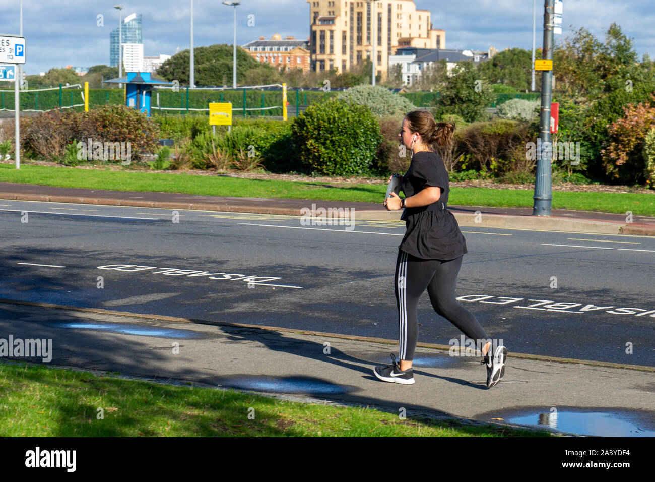 Eine junge Frau beim Joggen oder Laufen allein am Straßenrand Stockfoto