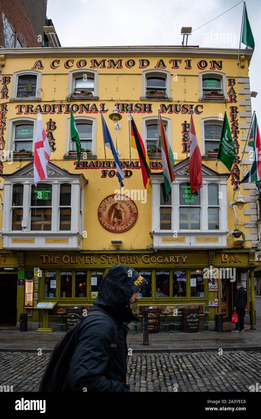 Ein junger Mann, der auf einer Straße im alten Stadtzentrum vorbeikommt. Typisch irisches Pub und Unterkunftgebäude im Hintergrund. Dublin, Irland. Stockfoto