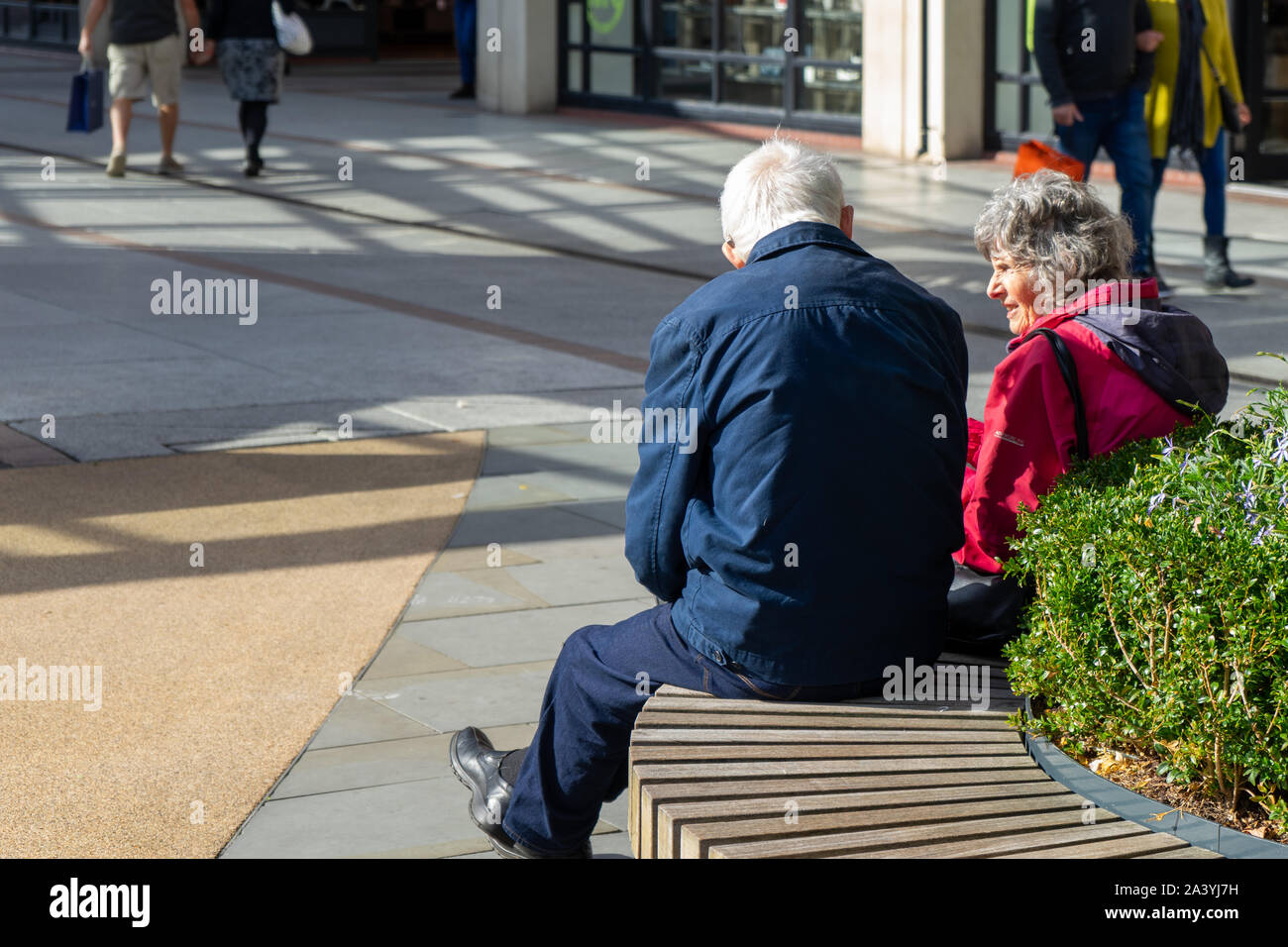 Ein älteres Ehepaar saß auf einer Bank in einem Einkaufszentrum oder das Einkaufszentrum Stockfoto