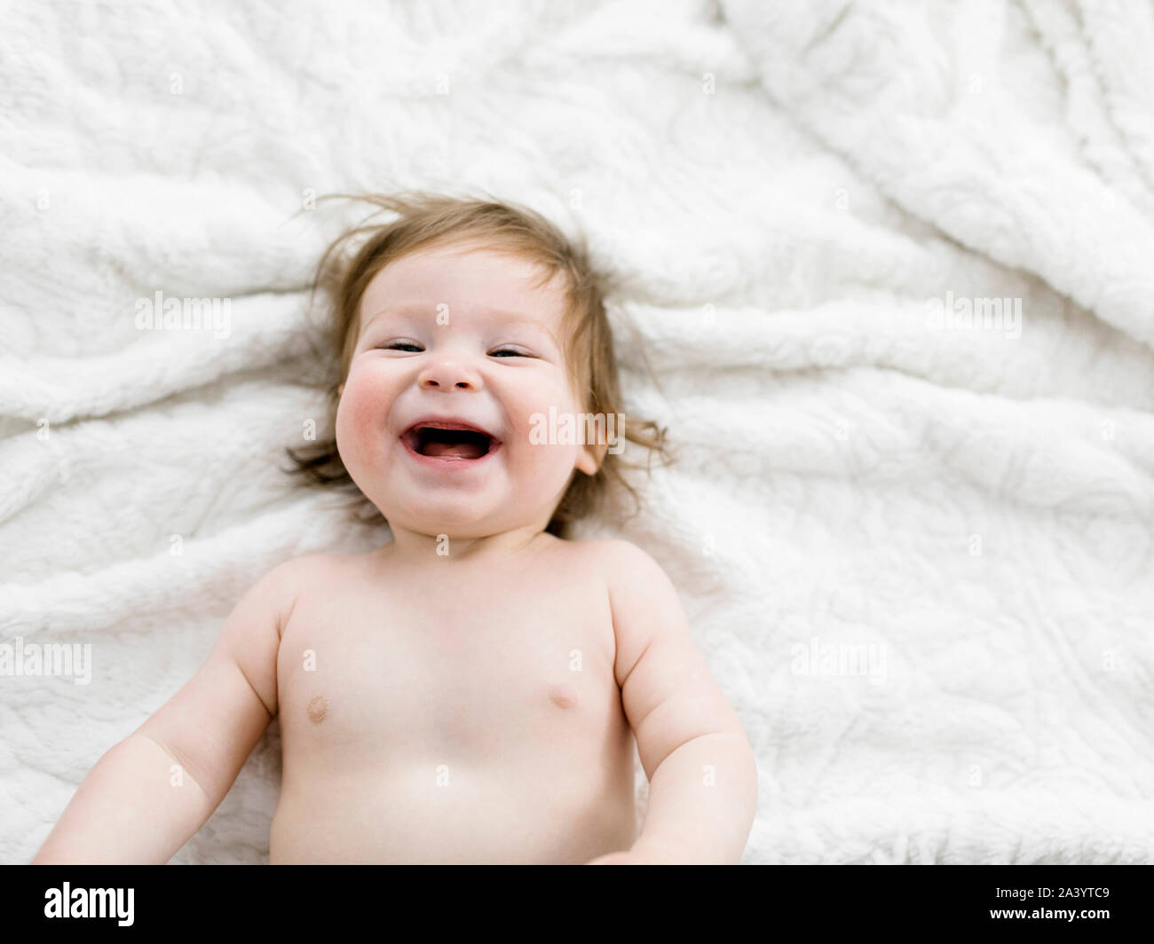 Lachendes Baby Mädchen liegt auf der Decke Stockfoto