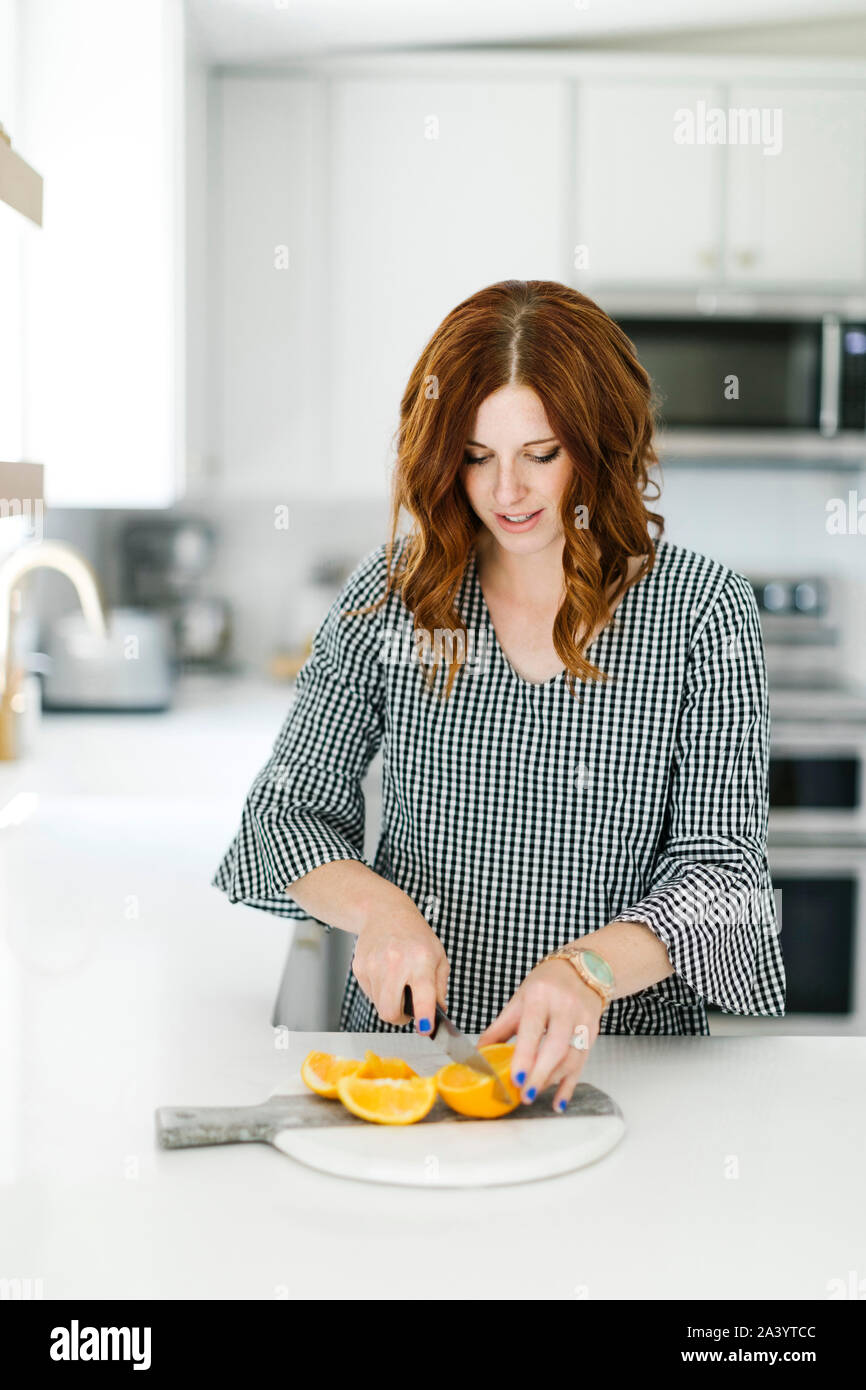 Frau slicing Orange in der Küche Stockfoto