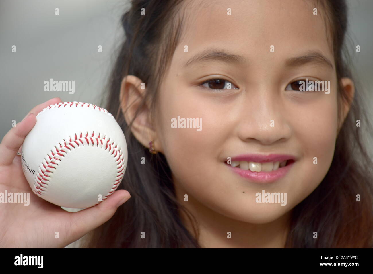 Passen Diverse weibliche Baseballspieler Kind Athlet lächelnd mit Baseball Stockfoto