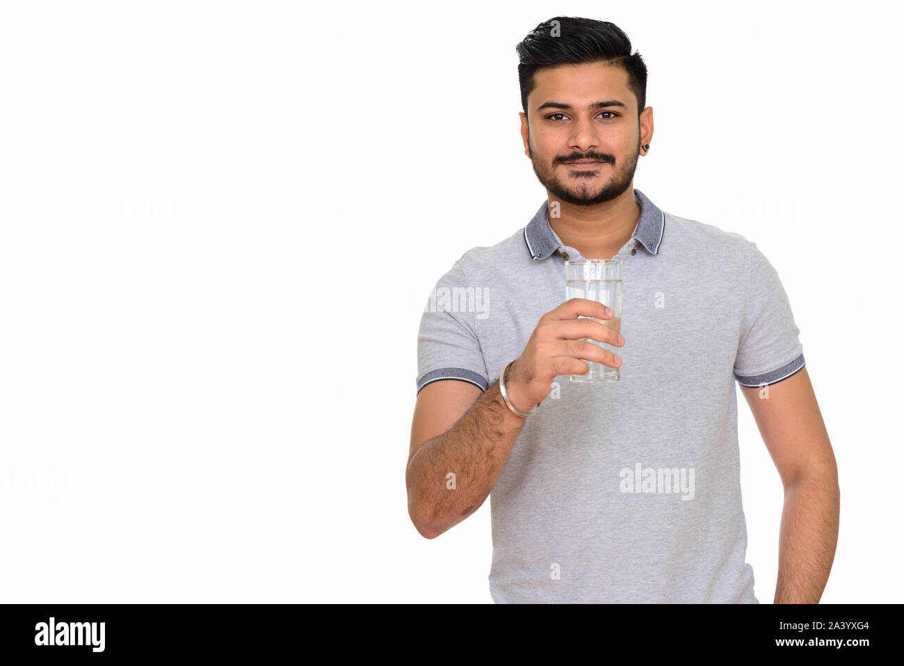 Junge schöne Indische Mann hält Glas Wasser Stockfoto