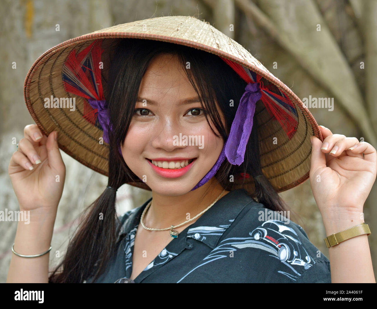 Junge vietnamesische Frau trägt eine asiatische konische Strohhut und ein Lächeln für die Kamera. Stockfoto