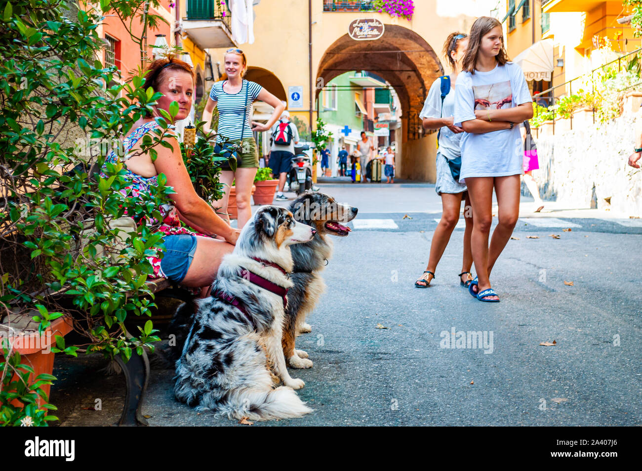 Monterosso al Mare, Italien - September 02, 2019: Einige Leute sitzen auf einer Bank mit ihren Hunden, andere sind Wandern, Reisen durch eine gemütliche belebten St Stockfoto