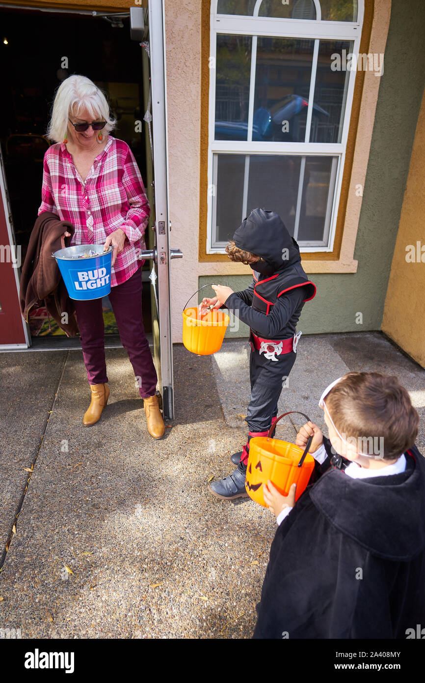 Zwei Jungen in Halloween Kostüme trick-or-Behandlung in Geschäften, auf der Straße in Windsor Town Green, in Sonoma County, Kalifornien, gekleidet. Stockfoto