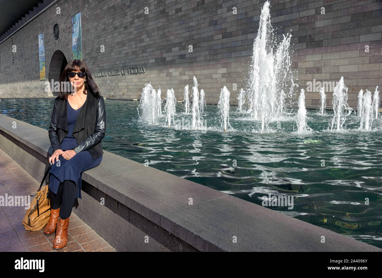 Frau sitzt auf der Kante eines Brunnen vor der Nationalgalerie von Victoria nach dem Besuch der Vincent Van Gogh Ausstellung. Stockfoto