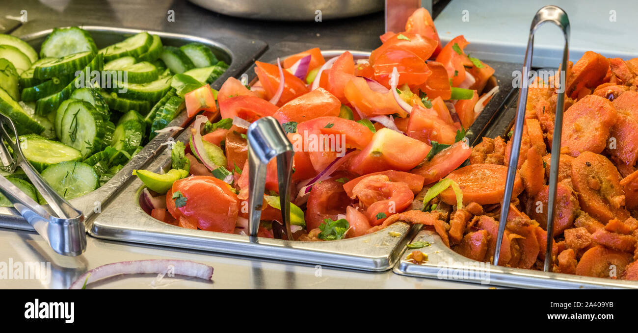 Zutaten auf einen falafel Bar mit Metall Gemüse Zangen Tomaten Karotten Gurken Stockfoto