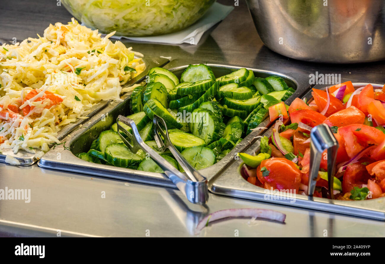 Zutaten auf einen falafel Bar mit Metall Gemüse Zangen Kohl Gurken Tomaten Stockfoto