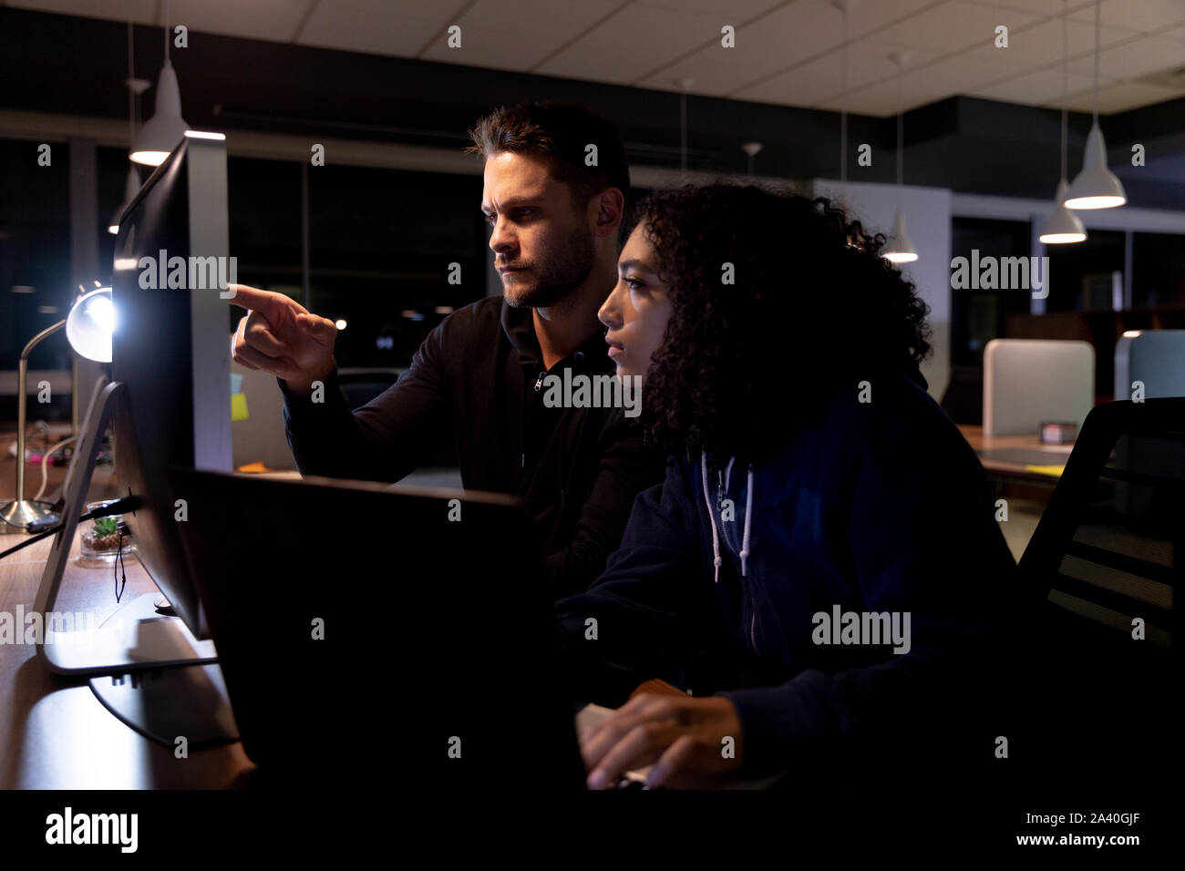Zwei junge kreative Fachleute, die spät in einem modernen Büro Stockfoto
