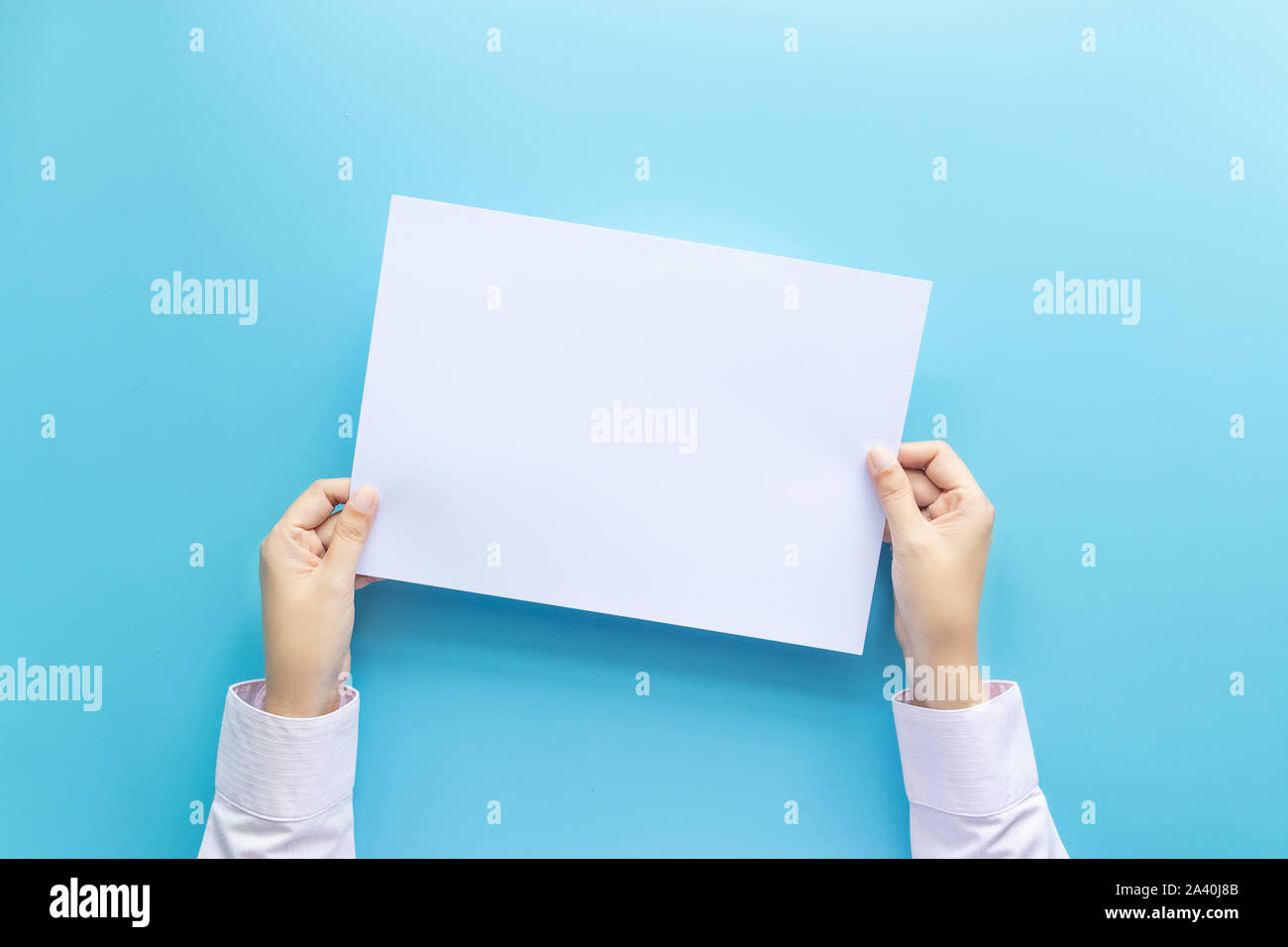 Die Hände schließen Holding leere weiße Leere Buchstaben Papier Für Flyer, Präsentation oder Einladung mock up auf einem blauen Hintergrund. Stockfoto