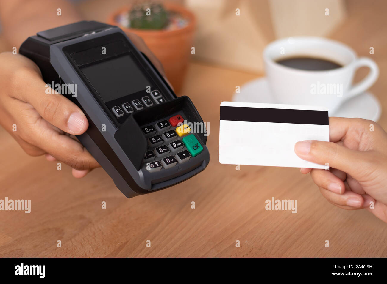 Hand der Kunde mit Kreditkarte für die Bezahlung am Point of Sale Terminal im Shop beim Shoppen, bargeldlose Technologie- und Kreditkartenzahlung con Stockfoto